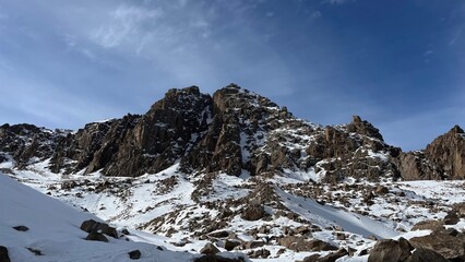 rugged winter mountain landscape with jagged rock formations and snow covered slopes under a clear blue sky