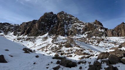 rugged winter mountain landscape with jagged rock formations and snow covered slopes under a clear blue sky