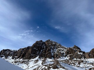 rugged winter mountain landscape with jagged rock formations and snow covered slopes under a clear blue sky
