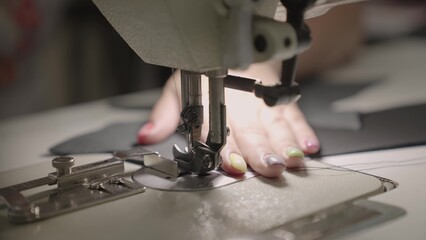 hands seamstress sew product from leather fabric sewing machine. concept female business work home. tailor sews high quality fabric. concept work private leather workshop motion. needle process sewing