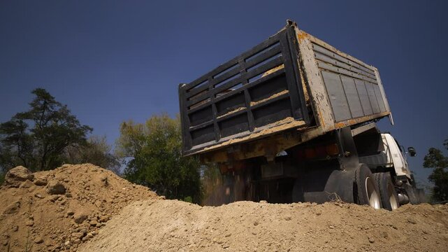 Trucks are dumping a large amount of soil onto the construction site.
