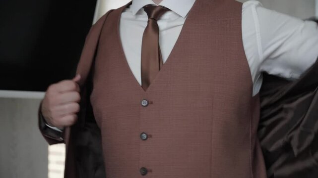A polished video showcases a sophisticated individual preparing for a formal occasion in a stylish brown suit. Watch as they fine-tune their look, exuding confidence against an elegant backdrop.