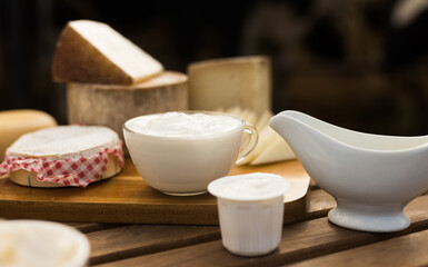 Milk, cottage cheese, cream, cheese on table against background of cows