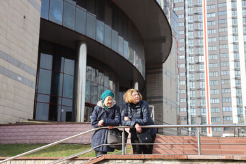 Two elderly ladies, mother and daughter, walking around the city, talking, laughing, drinking coffee. Active healthy lifestyle