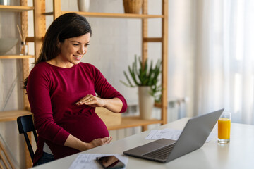 Pregnant woman having an online conference video call with her colleagues while working from home.