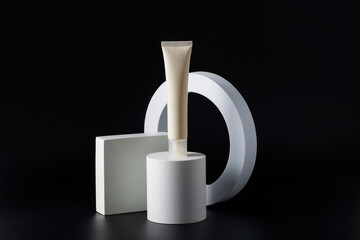 Plastic white tube for cream or lotion. Skin care or sunscreen cosmetic with stylish props on black background.