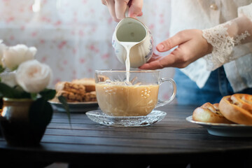 English breakfast, mourning routine. Woman pouring milk into cup of tea.