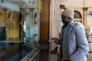 Young African man buying a train ticket at the station