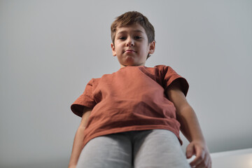 A confident boy stands tall, captured from a low-angle perspective, giving a sense of strength and...