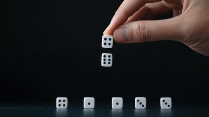 Hand Stacking Dice on a Dark Background