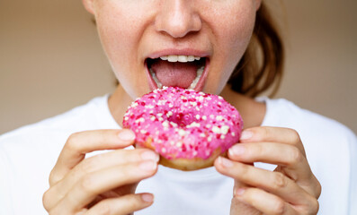 Closeup photo woman eating donut with pink glaze