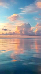 Obraz premium Serene sunset over calm ocean; pastel clouds reflected in tranquil water. Perfect for travel, meditation, or relaxation themes.