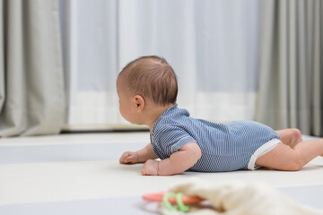 Fototapeta premium Newborn baby crawling on soft play mat