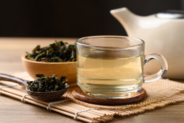 Hot green tea in cup glass, dried tea leaves and teapot on wooden background, Healthy drink