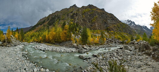Russia. Kabardino-Balkaria. Panoramic view of the Shkhelda mountain river surrounded by the Caucasus Mountains with glaciers feeding the muddy river.