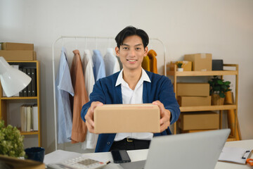 Confident small business owner handing over a packed parcel and smiling at camera