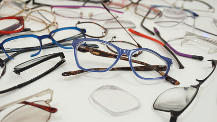 Assortment of broken glasses, broken hinges, missing lenses, cracked frames, deformed glasses. Mix...