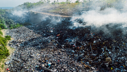 Burning landfill emitting smoke, highlighting environmental pollution and waste management...