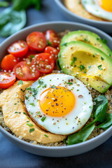 A bowl of food with a fried egg on top and a tomato and avocado salad underneath