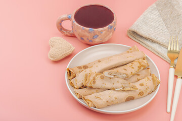 A cup of fragrant hibiscus tea and thin pancakes with cream. Good mood concept, cozy home comfort