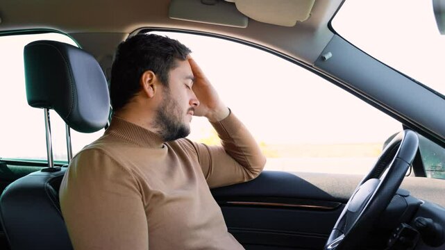 Side view young male driver closed his eyes and rests with his hand on the steering wheel