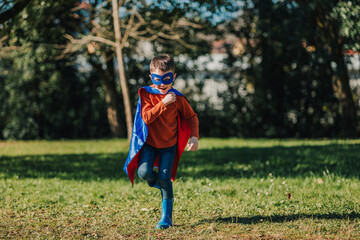 Young child dressed as a superhero plays in a park on a sunny afternoon, showcasing joy and imagination © Heart in pictures