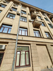 Fototapeta premium A towering beige residential building with repeating architectural elements, small balconies, and glass windows. This image showcases urban geometry and modern living in compact city spaces.
