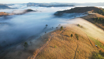 Aerial landscape view of the sea of fog flowing on hills with campsite by drone