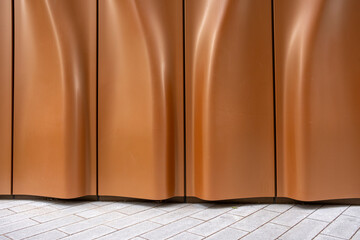 An elegantly designed curved wall with warm brown tones creates a captivating visual effect that enhances the surrounding architectural environment beautifully.