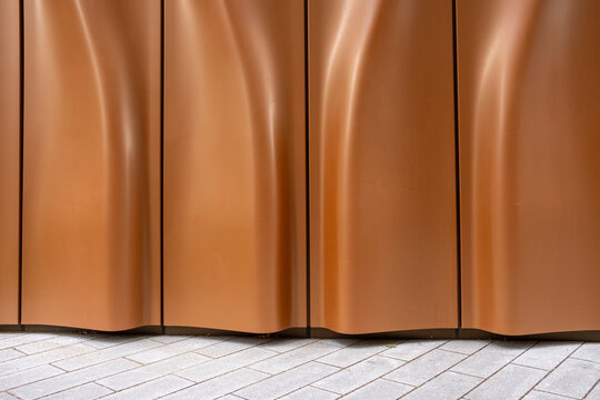 An elegantly designed curved wall with warm brown tones creates a captivating visual effect that enhances the surrounding architectural environment beautifully.