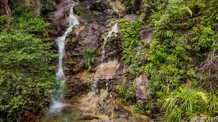 Lush tropical waterfall cascading over rocks in a vibrant green jungle, symbolizing tranquility and natural beauty for ecotourism