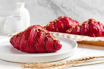 Red velvet croissant on a white plate.