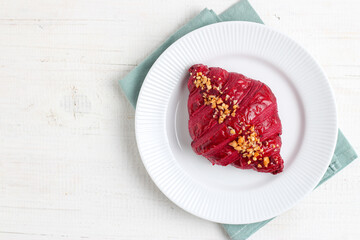 Red velvet croissant on a white plate.