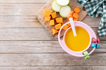 Bowl with baby food. vegetable puree on wooden table. Top view. Copy space