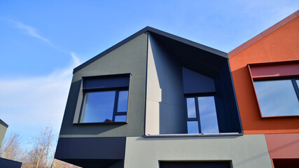 Terraced family homes in newly developed housing estate. The real estate market in the suburbs. New single family houses in a new development area. Residential homes with modern facade. 