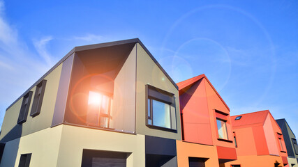 Terraced family homes in newly developed housing estate. The real estate market in the suburbs. New single family houses in a new development area. Residential homes with modern facade. 
