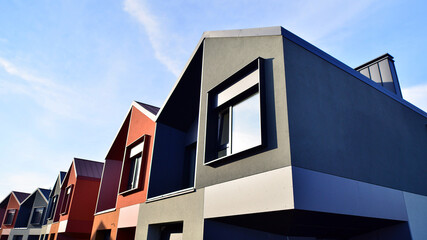 Terraced family homes in newly developed housing estate. The real estate market in the suburbs. New single family houses in a new development area. Residential homes with modern facade. 