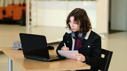 A girl immersed in her laptop studies in a spacious, bright room. This scene embodies the empowerment of young learners through technology and the shift toward virtual education.