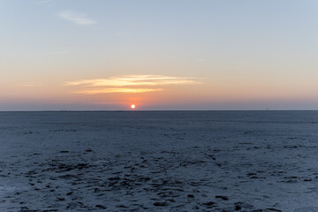 pristine sunset over white salt flats desert with dramatic orange sky at dusk