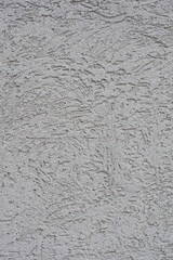 A close-up of a gray cement facade with a rough, textured surface