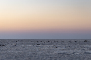 white salt flats desert with dramatic orange sunset sky at dusk