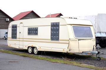 Old Classic Camper on wheels at the parking. White Travel Trailer at the city street. Five seater travel trailers parked in a city parking lot. Camping trailer. Moving house at the parking. Right view