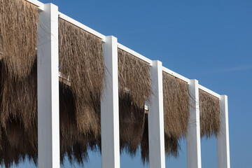 White wooden pergola with natural straw coverage