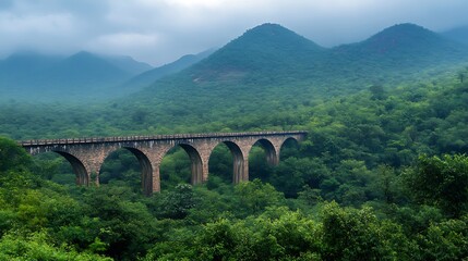 A scenic view of bridge amidst lush green forest and hillst