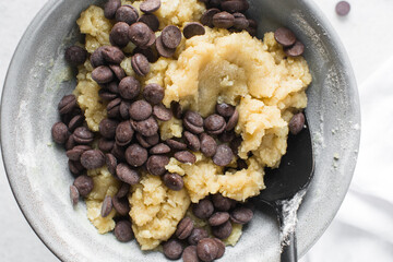 Overhead view of chocolate chip cookie dough, top view of homemade chocolate chip cookie dough in a bowl on a white background, process of making chocolate chip cookies