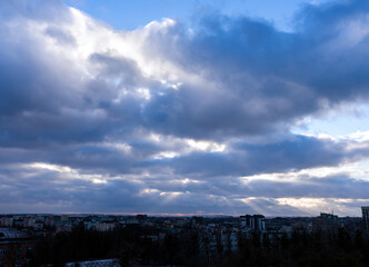 Dramatic blue-grey sky and rays of sun breaking through the clouds. Sunset. Natural background. Selective focus.