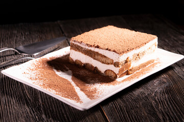 Tiramisu cake dessert served with coffee, biscuit and cocoa on dark background.spoon. Dessert. Food Concept