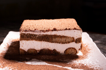 Tiramisu cake dessert served with coffee, biscuit and cocoa on dark background.spoon. Dessert. Food Concept