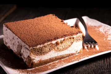 Tiramisu cake dessert served with coffee, biscuit and cocoa on dark background.spoon. Dessert. Food Concept