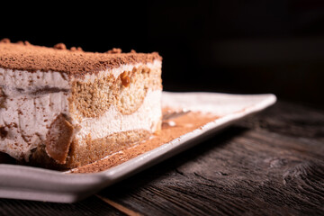 Tiramisu cake dessert served with coffee, biscuit and cocoa on dark background.spoon. Dessert. Food Concept